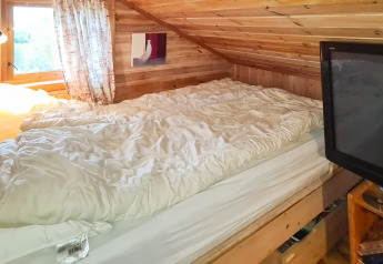 Slaapkamer met schuin houten plafond, tweepersoonsbed, TV en raam in het 12-persoons vakantiehuis in Tau.