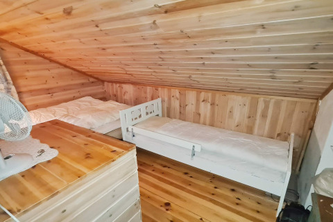 Dormitorio con dos camas individuales y techo de madera inclinado en una casa vacacional en Tau, Dinamarca.