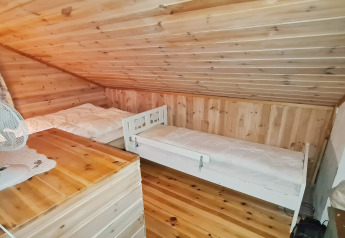 Camera da letto con due letti singoli e soffitto inclinato in legno in un rifugio a Tau, Danimarca.