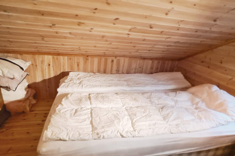 Slaapkamer met houten wanden en schuin plafond in 12-persoons vakantiehuis in Tau, Denemarken, met tweepersoonsbed.