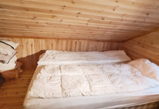 Chambre avec murs et plafond en bois dans maison de vacances 12 personnes à Tau, Danemark, avec lit double.