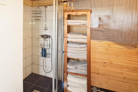 Bagno nella casa vacanze per 12 persone a Tau, Danimarca, con doccia, scaffale di asciugamani e legno.