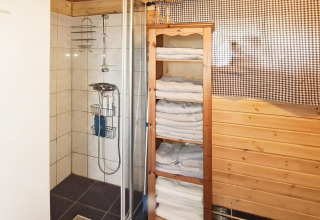 Bagno nella casa vacanze per 12 persone a Tau, Danimarca, con doccia, scaffale di asciugamani e legno.