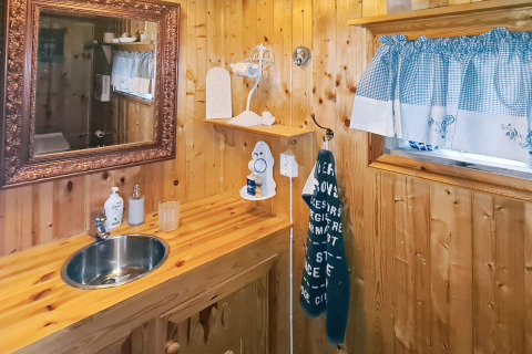 Gezellige houten badkamer met spiegel, wastafel en raam in een vakantiehuis in Tau, Denemarken.