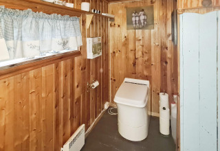 Salle de bain avec des panneaux en bois, toilettes modernes, étagère décorative et rideau à carreaux.