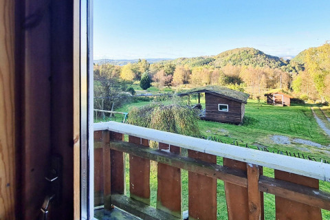 Vue d’un lodge près du « gîte 12 personnes à Tau » sur des champs, arbres et cabanes au Danemark.