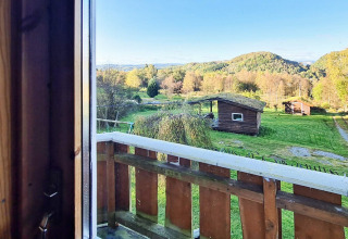 Uitzicht vanuit een lodge bij ‘12-persoons vakantiehuis in Tau’ op groene velden, bomen en hutten in Denemarken.