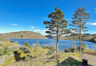 Smuk udsigt over søen og bakkerne fra HUS 55762 HYTTE A i Danmark med klart blå himmel.
