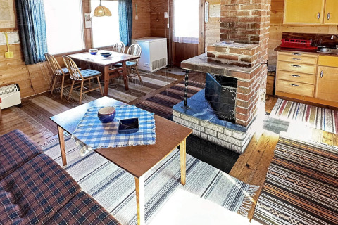 Hyggelig stue i HUS 55762 HYTTE A i Danmark med træmøbler, pejs og køkken i traditionel stil.