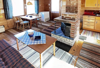 Hyggelig stue i HUS 55762 HYTTE A i Danmark med træmøbler, pejs og køkken i traditionel stil.