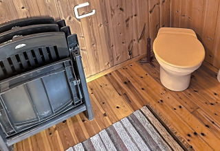 Billede af et træbeklædt toiletområde med plaststole, gulvtæppe og brunt toiletsæde i HUS 55762 HYTTE A.