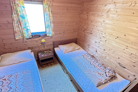 Et hyggeligt værelse på HUS 55762 HYTTE A i Danmark med to enkeltsenge, trævægge og farverige gardiner.