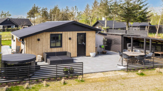 Modern 4-sterren vakantiehuis in Løgstør met terras, zithoek en jacuzzi in een groene omgeving.