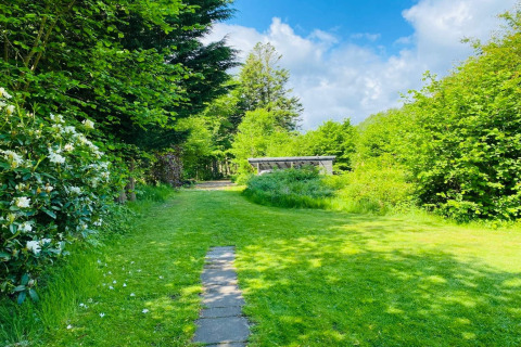 Groene tuin met pad en bloeiende struiken bij 6-persoons vakantiehuis in Bogense, Denemarken op een zonnige dag.