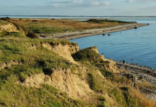 Kystlandskab ved søen nær 6-personers feriehus i Bogense, Danmark, med klipper og blå himmel.