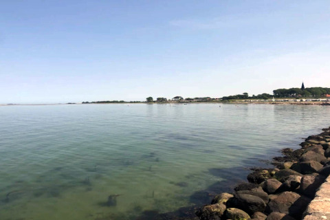 Vue depuis une maison de vacances pour 6 personnes à Bogense, Danemark, avec mer calme et ciel bleu.