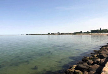 Vue depuis une maison de vacances pour 6 personnes à Bogense, Danemark, avec mer calme et ciel bleu.