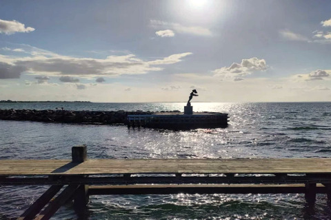 Vue ensoleillée sur la mer avec jetée et statue près d'une maison de vacances 6 personnes à Bogense, Danemark.