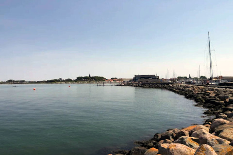 Vue côtière depuis une maison de vacances à Bogense, Danemark, mer calme, rochers et bateaux à quai.