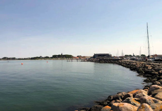 Vue côtière depuis une maison de vacances à Bogense, Danemark, mer calme, rochers et bateaux à quai.
