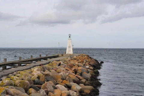 Rotsenpier met vuurtoren aan zee naast het 6-persoons vakantiehuis in Bogense, Denemarken.