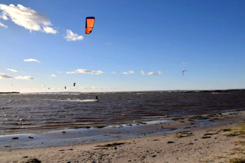 Kitesurfeurs sur la plage à Bogense, Danemark, profitant du beau temps sous un ciel bleu et clair.