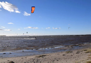 Kitesurfers aan de kust van Bogense, Denemarken, genieten van een zonnige dag met blauwe lucht.