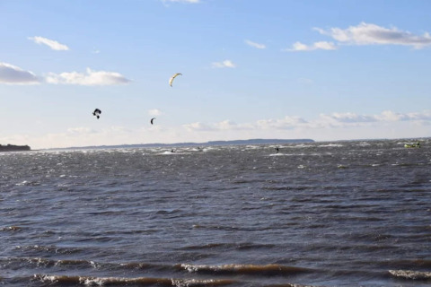 Kitesurfers op het water gezien vanaf 6-persoons vakantiehuis in Bogense, Denemarken, heldere lucht.