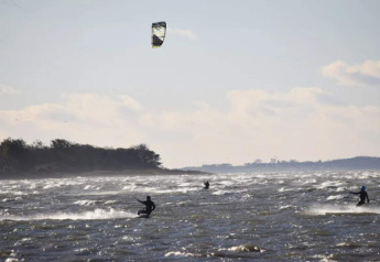 Kitesurfers ride the waves near the coast by the 6 person holiday home in Bogense, Denmark.