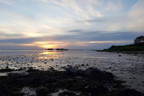 Coucher de soleil sur la plage près du gîte 6 personnes à Bogense, Danemark, ciel nuageux et eau calme.