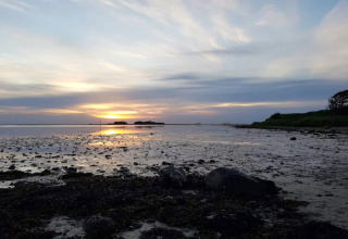 Coucher de soleil sur la plage près du gîte 6 personnes à Bogense, Danemark, ciel nuageux et eau calme.