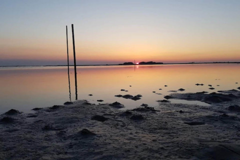 Zonsondergang bij een ondiepe kust bij 6-persoons vakantiehuis in Bogense, Denemarken, met reflecterende palen.