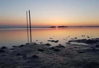 Zonsondergang bij een ondiepe kust bij 6-persoons vakantiehuis in Bogense, Denemarken, met reflecterende palen.