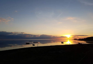 Solnedgang over stille vand ved '6 personers feriehus i Bogense', Danmark, med både og smuk himmel.
