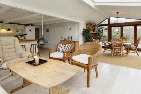 Lyst og rummeligt opholdsområde i sommerhus i Bogense, Danmark, med moderne møbler og store vinduer.