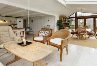 Ruime, lichte leefruimte in een vakantiehuis in Bogense, Denemarken, ingericht met rieten stoelen en grote ramen.