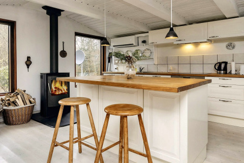 Cuisine chaleureuse d'une maison de vacances à Bogense, Danemark, avec poêle à bois et îlot en bois.