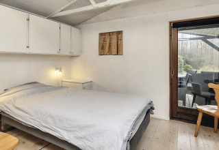 Slaapkamer in een 6-persoons vakantiewoning in Bogense, Denemarken, met tweepersoonsbed en terrasdeur.