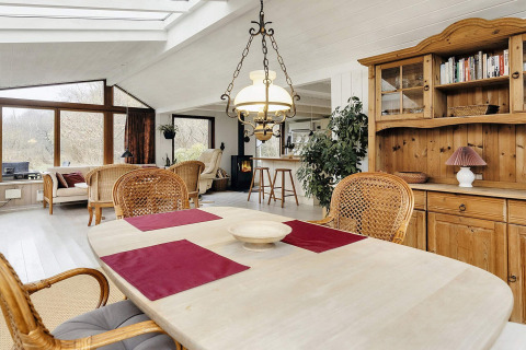 Salón y comedor en casa de vacaciones para 6 personas en Bogense, Dinamarca, con muebles de madera y grandes ventanales.