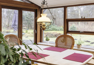 Eethoek met ruime ramen, houten stoelen en tuinzicht in een vakantiehuis in Bogense, Denemarken.
