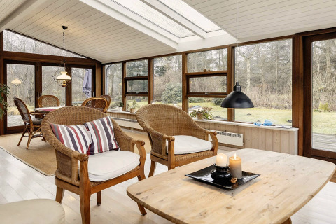 Véranda lumineuse avec fauteuils en osier dans une maison de vacances pour 6 personnes à Bogense, Danemark.