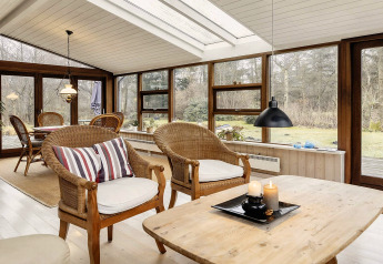 Véranda lumineuse avec fauteuils en osier dans une maison de vacances pour 6 personnes à Bogense, Danemark.