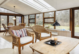 Zonnige veranda met rotan stoelen in een vakantiehuis voor 6 personen in Bogense, Denemarken.