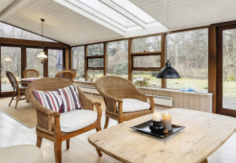 Zonnige veranda met rotan stoelen in een vakantiehuis voor 6 personen in Bogense, Denemarken.