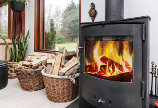 Gemütlicher Kamin mit Holzkorb in einem Ferienhaus in Bogense, Dänemark, gemütlich eingerichtet.