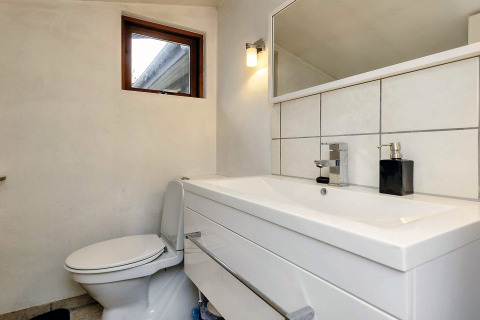 Salle de bain moderne dans une maison de vacances à Bogense, Danemark, avec lavabo, toilettes et miroir.