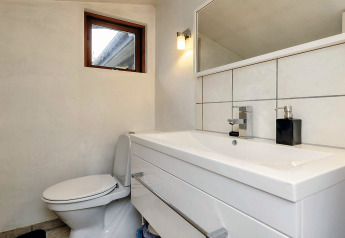 Salle de bain moderne dans une maison de vacances à Bogense, Danemark, avec lavabo, toilettes et miroir.