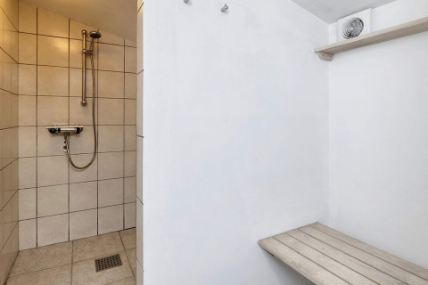 Zona de ducha con banco y ventilador en una casa de vacaciones para 6 personas en Bogense, Dinamarca.