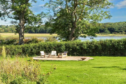 Houten terras met drie stoelen in groene tuin, uitzicht op natuur bij 4-sterren vakantiehuis in Rønde.