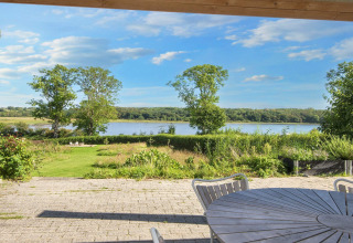 Blick von der Terrasse des "4 star holiday home in Rønde" mit Garten, See und Sitzbereich in Dänemark.